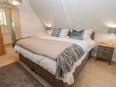 A bedroom with a large bed with pillows a throw and bedside tables with lamps at Fenwick Retreat at Fenwick Lodge Fenwick near Ponteland
