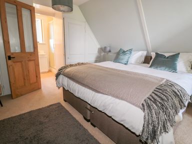 A bedroom with a bed lamp and an open door leading to a bathroom at Fenwick Retreat at Fenwick Lodge in Fenwick near Ponteland