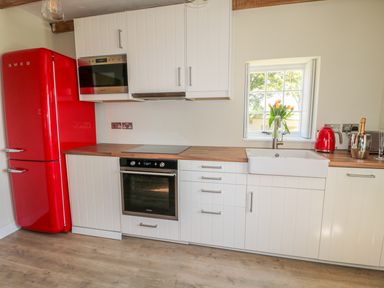 A kitchen with a red refrigerator white cabinets a wooden countertop a white sink a window and appliances at Fenwick Retreat at Fenwick Lodge in Fenwick near Ponteland