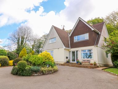 A house with a circular driveway and landscaped garden at Trevow in Camborne