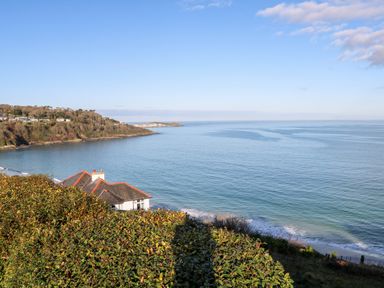 A coastal view with houses near the shoreline and a hillside covered with vegetation at Trevow in Camborne