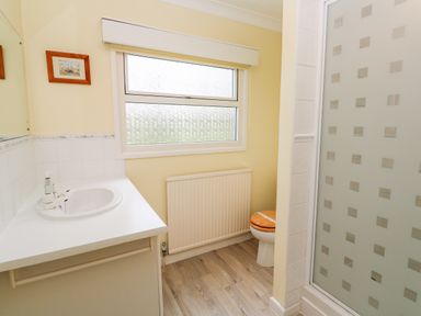 A bathroom with a sink countertop mirror window radiator toilet and shower with a patterned glass door at Trevow Camborne
