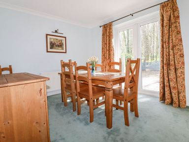 A dining room with wooden table and chairs and floral curtains at Trevow in Camborne