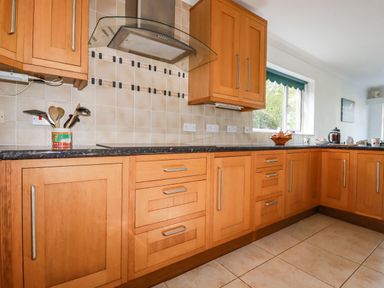 A kitchen with wooden cabinets a window and kitchen utensils at Trevow Camborne
