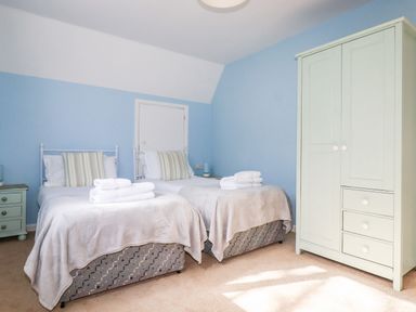 A bedroom with two single beds with towels on them a nightstand and a wardrobe at Trevow Camborne