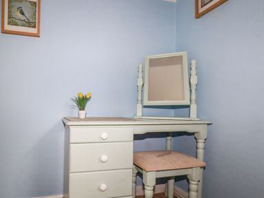 A dressing table with a small potted plant and a stool in a blue room at Trevow in Camborne