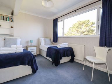 A bedroom with two single beds bedside table and chair at Trevow in Camborne