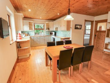 A kitchen and dining area with wooden floor ceiling and table with six black chairs at Silver Birch in Dromelihy Cooraclare County Clare