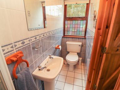A small bathroom with a toilet sink towel and stained glass window at Silver Birch in Dromelihy Cooraclare County Clare