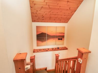 A wooden staircase with a three-panel sunset artwork and small decorative items on a wooden shelf at Silver Birch in Dromelihy Cooraclare County Clare