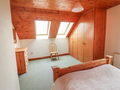 A bedroom with a wooden bed a wooden chair a wooden dresser built in wooden wardrobe and two skylights at Silver Birch in Dromelihy Cooraclare County Clare