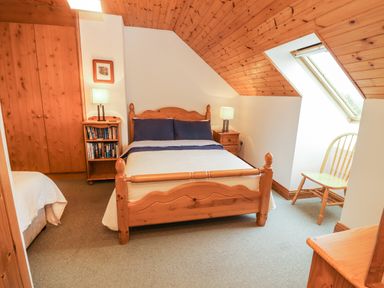 A bedroom with a wooden double bed blue pillows wooden furniture and a skylight window at Silver Birch in Dromelihy Cooraclare County Clare