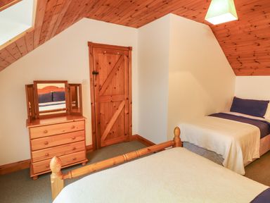 A bedroom with two single beds a wooden chest of drawers with a mirror and a wooden door at Silver Birch in Dromelihy Cooraclare County Clare