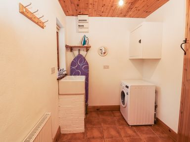 A laundry room with a washing machine sink ironing board and coat hooks at Silver Birch in Dromelihy Cooraclare County Clare