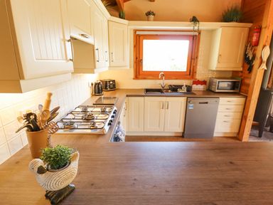 A kitchen with wooden countertop and cabinets a gas stove a microwave a dishwasher and a window at Jemima Lodge in Tattershall