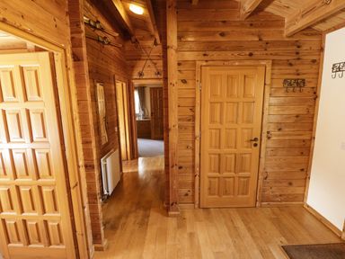 A wooden hallway with doors leading to other rooms and skis mounted on the wall at Jemima Lodge in Tattershall