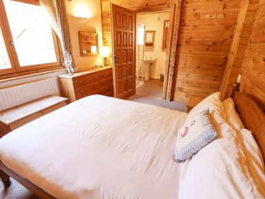 A bedroom with a wooden bed and dresser next to a window at Jemima Lodge in Tattershall