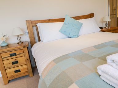 A bedroom with a wooden bed and bedside tables with lamps at Tyn Y Buarth in Dyffryn Ardudwy