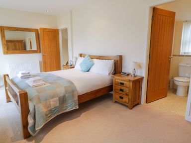 A bedroom with a wooden bed and bedside tables with lamps at Tyn Y Buarth in Dyffryn Ardudwy