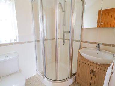 A bathroom with a toilet shower unit and sink cabinet at Tyn Y Buarth in Dyffryn Ardudwy