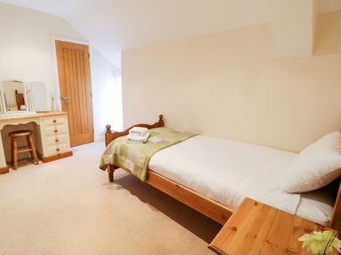 A bedroom with a single bed a wooden dressing table and stool at Tyn Y Buarth in Dyffryn Ardudwy