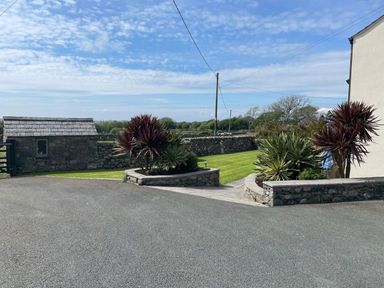 A driveway with stone flower beds and grass lawn surrounded by stone walls at Tyn Y Buarth in Dyffryn Ardudwy
