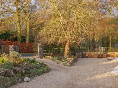 An outdoor garden area with gravel pathways trees and brick walls at Sykes Lodge in Malton