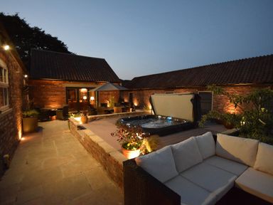An outdoor patio area with a hot tub seating and plants at Sykes Lodge in Malton
