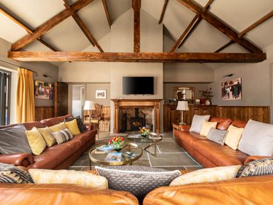 A living room with leather sofas cushions coffee tables fireplace and exposed wooden beams at Sykes Lodge in Malton