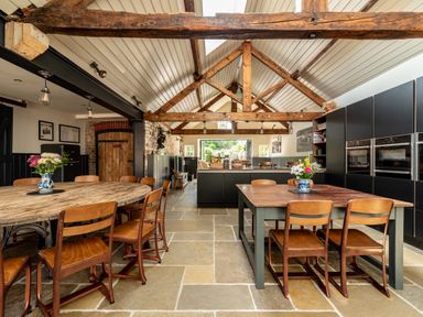 A kitchen and dining area with wooden tables and chairs under exposed wooden beams at Sykes Lodge in Malton