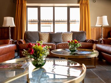 A living room with leather sofas cushions lamps and flower vases on glass coffee tables at Sykes Lodge in Malton