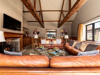 A living room with leather sofas wooden beams stone floor and a fireplace at Sykes Lodge in Malton