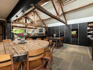 A kitchen with wooden tables and chairs black cabinets and exposed wooden beams at Sykes Lodge in Malton