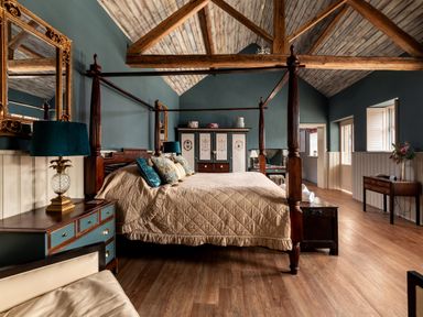 A bedroom with a four-poster bed blue walls wooden ceiling beams and wooden furniture at Sykes Lodge in Malton