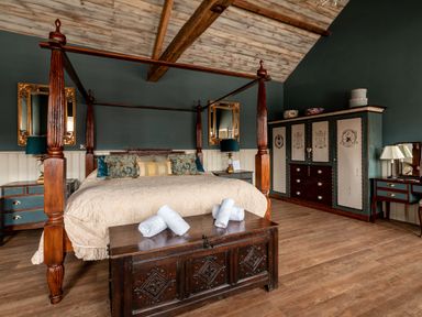 A bedroom with a four-poster bed side tables mirrors and a wardrobe at Sykes Lodge in Malton