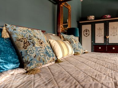 A bed with decorative pillows in a bedroom with a cabinet and a mirror at Sykes Lodge in Malton