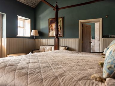 A bedroom with a four-poster bed a sofa a lamp and a framed picture at Sykes Lodge in Malton