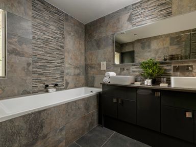 A bathroom with a bathtub a double sink vanity and a mirror at Sykes Lodge in Malton