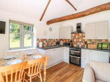 A kitchen with wooden dining table and chairs and tiled backsplash at Sparrow Barn in Reepham
