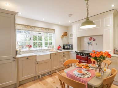 A kitchen with a dining table set with food and flowers at Rookwood in Drewsteignton