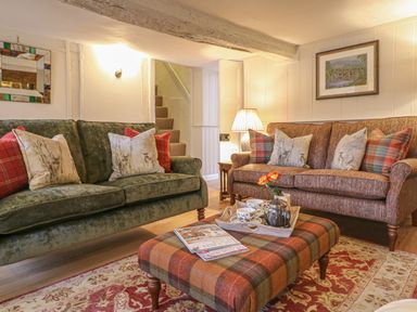 A living room with two sofas cushions a patterned ottoman and a side table with a lamp at Rookwood in Drewsteignton