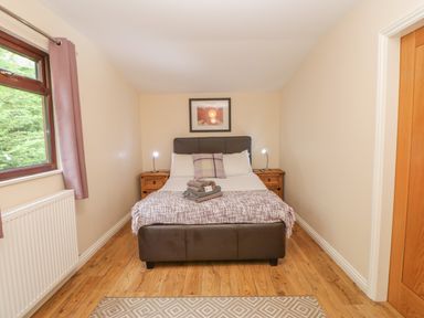 A bedroom with a double bed between two wooden nightstands and a window with curtains at Orchid Lodge in Saltburn-by-the-Sea