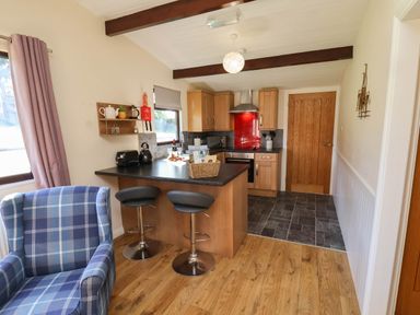 A kitchen with bar stools and kitchen appliances at Orchid Lodge in Saltburn-by-the-Sea