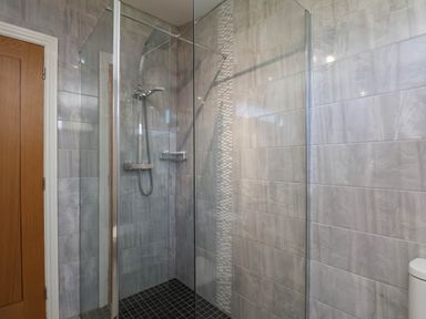 A shower with glass door and tiles at Orchid Lodge Saltburn-by-the-Sea