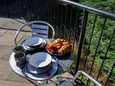 A table set with plates and cups along with croissants and fruit at Orchid Lodge in Saltburn-by-the-Sea