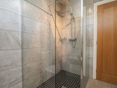 A shower with glass walls and a tiled floor at Foxglove Lodge in Saltburn-By-The-Sea