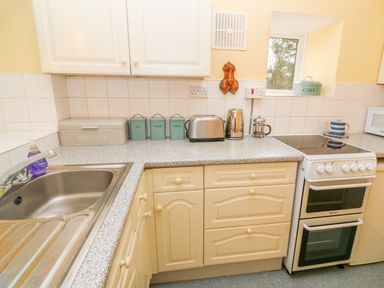 A kitchen counter with a sink toaster kettle canisters and stove at Higher Lampra in Mullion
