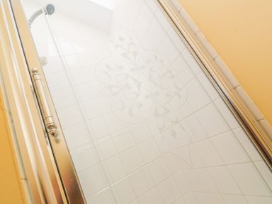 A shower area with patterned white tiles and a metal framed glass door at Higher Lampra in Mullion