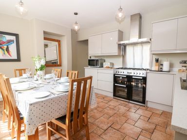 A kitchen with a dining table set for six with wooden chairs and an oven with cabinets at The Cottage at Broadway in Broadway