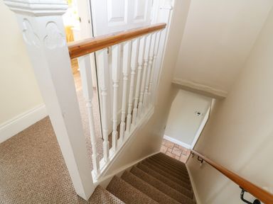 Stairs with carpet and wooden handrails leading down to a tiled floor at The Cottage at Broadway in Broadway